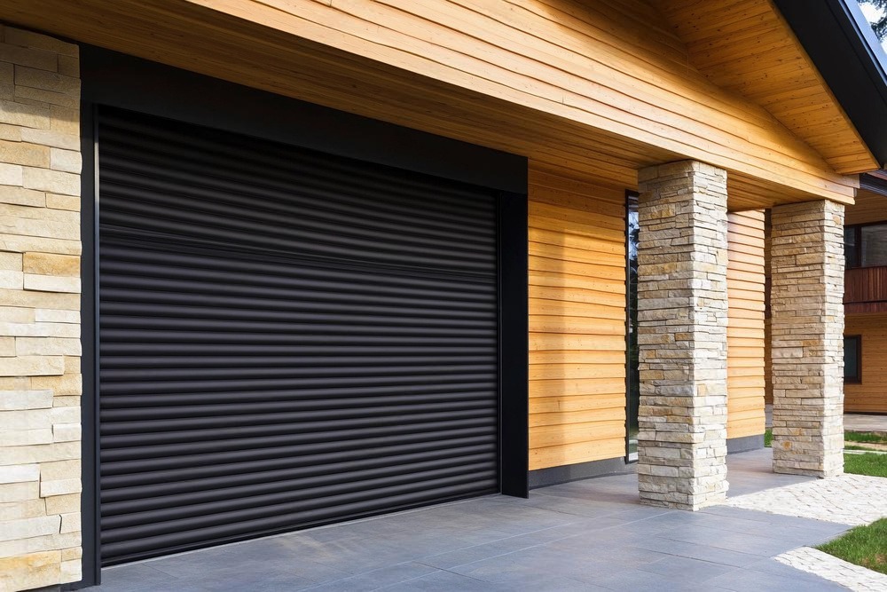 A black roller door on a wooden and stone house.
